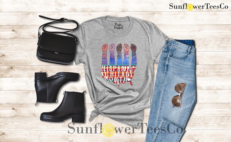 May include: A gray t-shirt with a graphic of raised fists in front of a stylized map of the United States. The graphic includes the text "Hispanic Heritage Month".