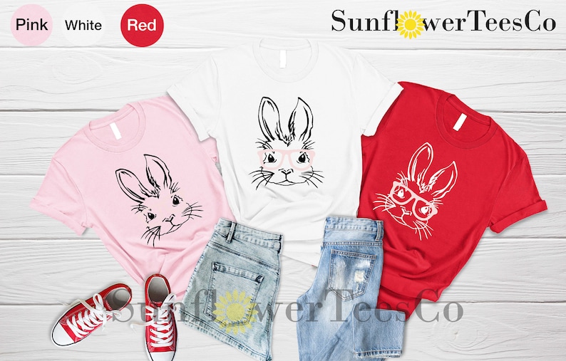 May include: Three t-shirts with a graphic of a bunny wearing glasses. The shirts are pink, white, and red. The text "Sunflower TeesCo" is visible at the top of the image.