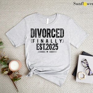May include: Gray t-shirt with black text that reads "DIVORCED (FINALLY) EST.2025".