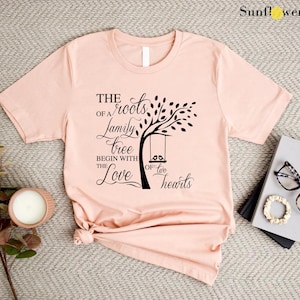 a pink t - shirt with a tree on it next to a pair of sunglasses