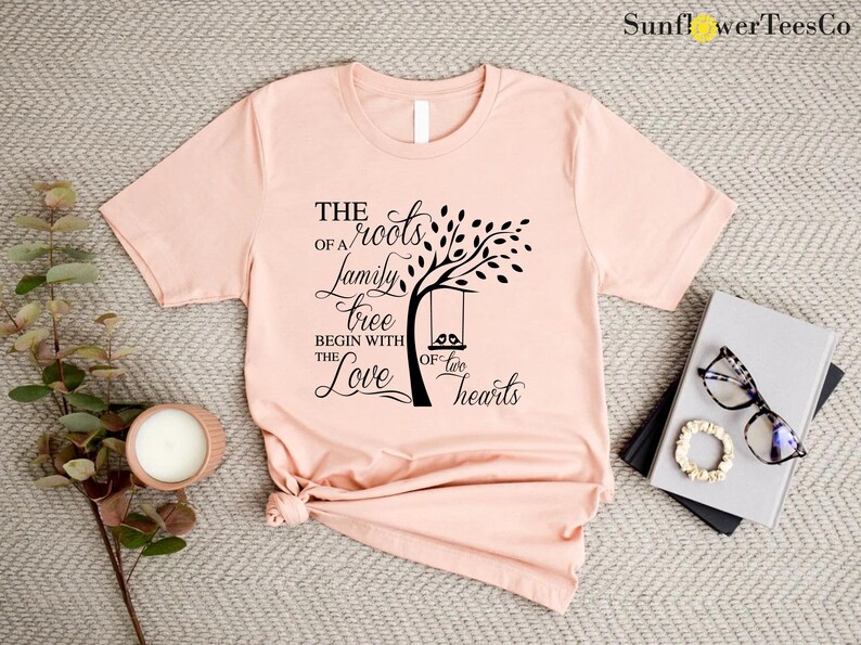 a pink t - shirt with a tree on it next to a pair of sunglasses