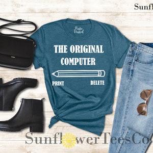 K&ouml;nnte beinhalten: Ein blaues T-Shirt mit dem Text "THE ORIGINAL COMPUTER" und einer Bleistiftgrafik mit den W&ouml;rtern "PRINT" und "DELETE" darunter.