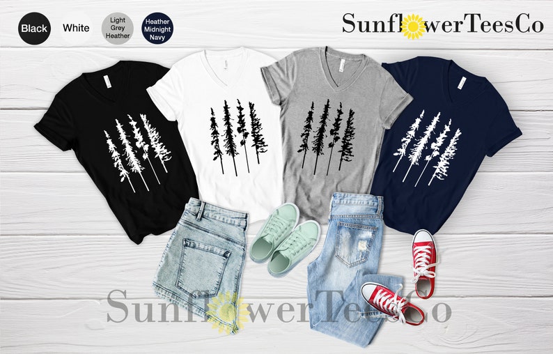 Op de afbeelding: Vier V-hals T-shirts met een afbeelding van een rij van vijf dennenbomen. De shirts zijn in zwart, wit, grijs melange en marineblauw. De tekst "SunflowerTeesCo" staat bovenaan de afbeelding.