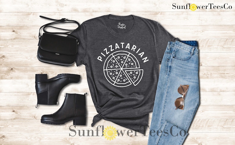 May include: A dark gray t-shirt with the text "Pizzatarian" in white lettering. The text is above a graphic of a pizza slice with white outlines.