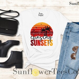 May include: White t-shirt with a retro sunset graphic and the text "chasing sunsets". The shirt is paired with blue jeans, a black crossbody bag, and black ankle boots.