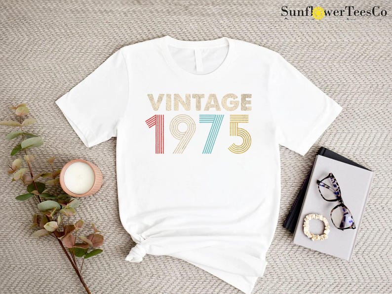 May include: White t-shirt with the text "Vintage 1975" in rainbow colors. The numbers are in a retro font style.