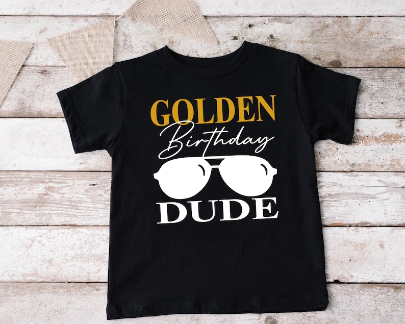 a black shirt with a gold birthday dude on it