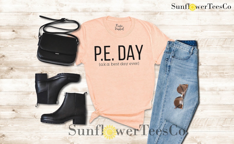 Op de afbeelding: Perzikkleurige T-shirt met zwarte tekst die "P.E. DAY (aka. best day ever)" luidt.