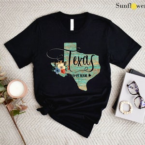 a t - shirt with the word texas on it next to a pair of sunglasses