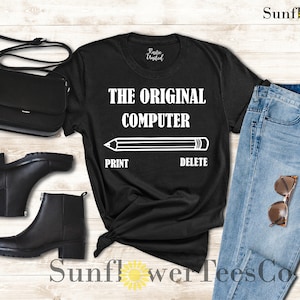 K&ouml;nnte beinhalten: Schwarzes T-Shirt mit wei&szlig;em Text, der "The Original Computer" lautet, mit einer Bleistiftgrafik und den W&ouml;rtern "Print" und "Delete" unter dem Bleistift.