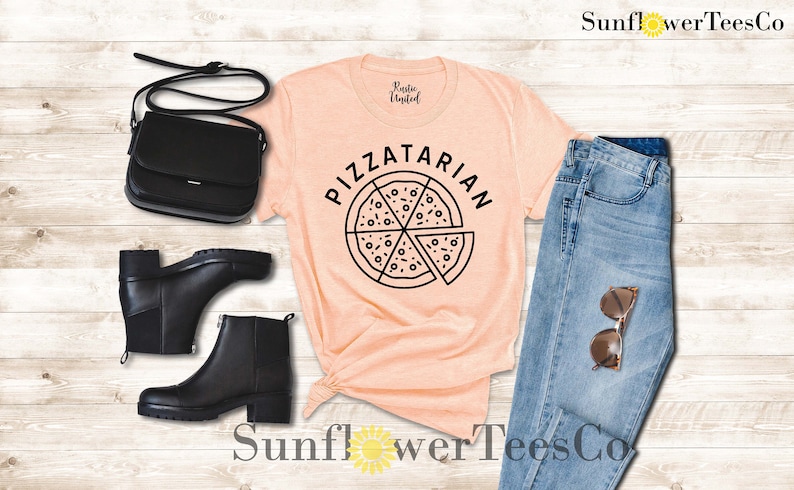 May include: A peach-colored t-shirt with the text "PIZZATARIAN" and a black and white illustration of a pizza slice. The shirt is paired with blue jeans, black boots, and a black purse.