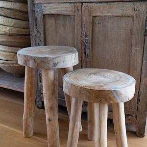 two teak nesting stools in front of an antique buffet in a dining room with paper mache bowls