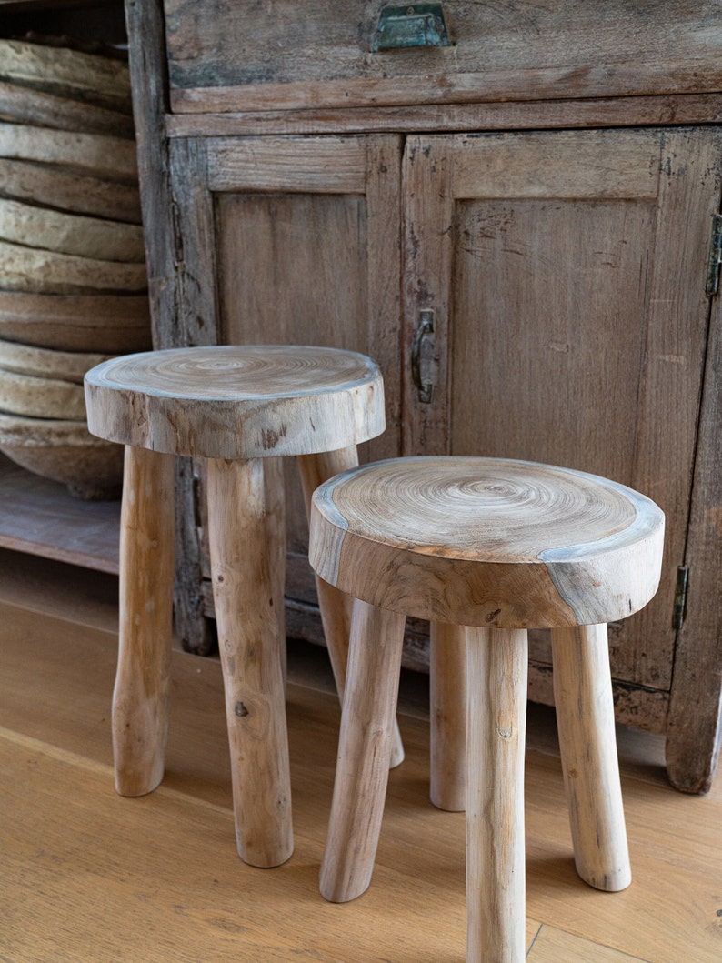 two teak nesting stools in front of an antique buffet in a dining room with paper mache bowls