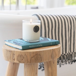 Teak stool used as a bath caddy with scented candle and turkish towel