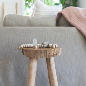 teak stool with a gold gilded crystal point and sage bundle