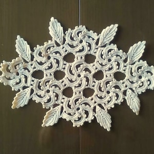 May include: A white crocheted doily with a delicate floral design. The doily is made with a fine thread and has a lacy appearance.