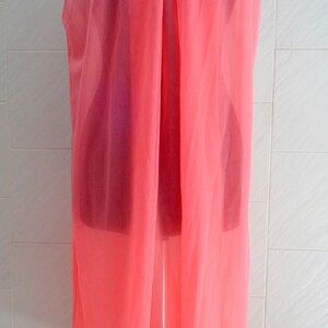 May include: A pink sleeveless slip with a white lace trim around the neckline and hem.