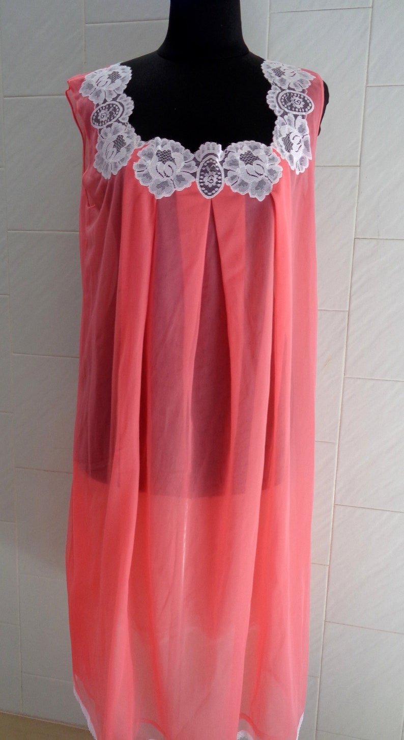 May include: A pink sleeveless nightgown with white lace trim around the neckline.
