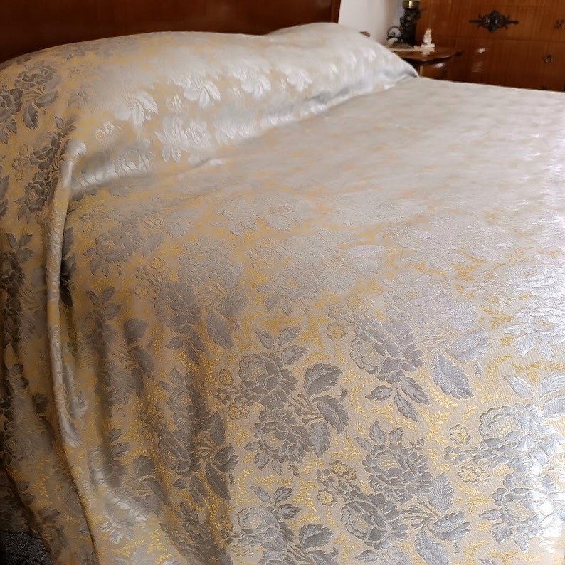 May include: A bed with a floral patterned duvet cover and pillowcase. The bedding is cream-colored with a silver and gold floral design. The bed is made up and ready for use.