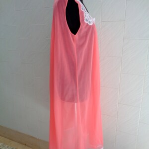 May include: A pink sheer nightgown with a white lace trim around the neckline. The gown is sleeveless and has a flowing silhouette.