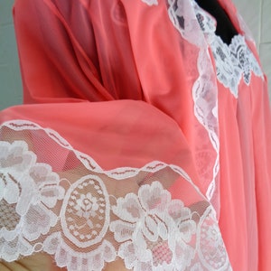 May include: A pink sheer nightgown with white lace trim. The lace features a floral design.