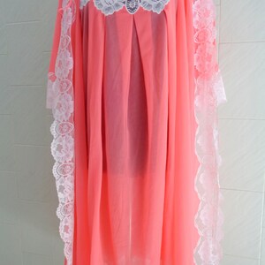 May include: A pink sheer nightgown with white lace trim. The gown has a scoop neck and is made of a lightweight fabric.