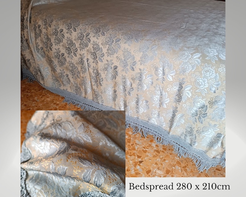 May include: A bedspread with a floral design in silver and gold hues. It features a light blue fringe trim. The dimensions are 280 x 210cm, equivalent to approximately 110 x 83 inches. The text on the image reads 'Bedspread 280 x 210cm'.