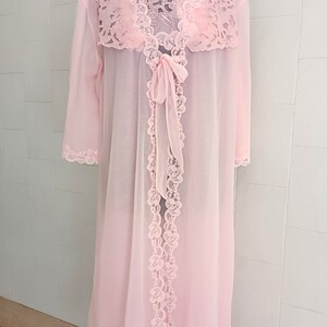 May include: A pink sheer robe with lace trim and a bow tie. The robe has long sleeves and a long length.