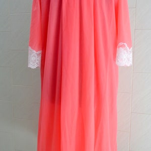 May include: A pink sheer robe with white lace trim around the neckline, sleeves, and hem.