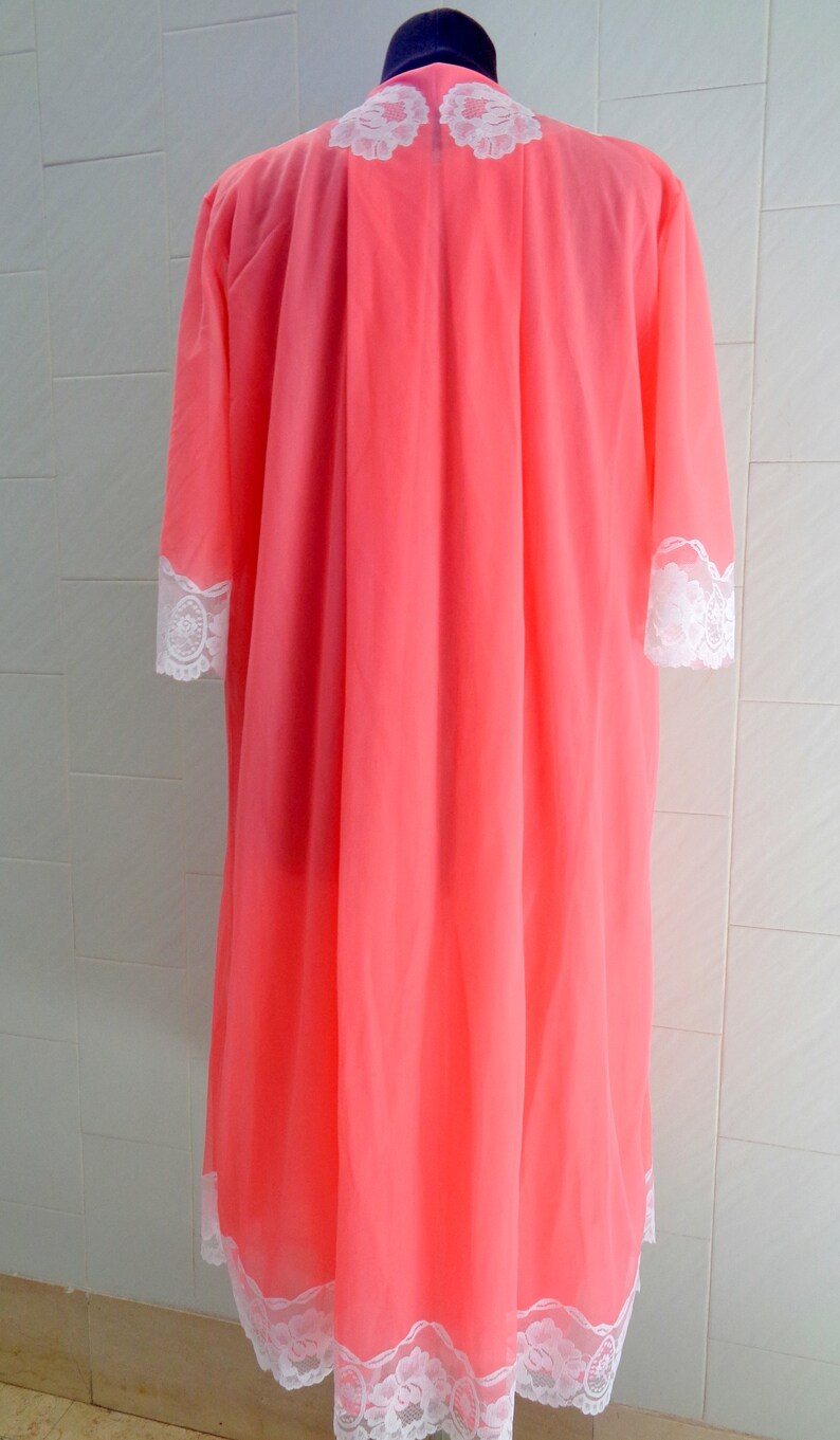 May include: A pink sheer robe with white lace trim around the neckline, sleeves, and hem.