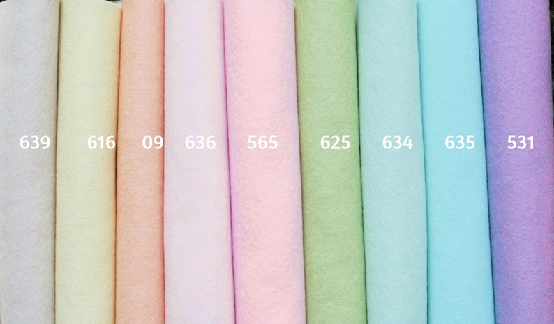 May include: A collection of fabric rolls in various pastel colors, including white, yellow, peach, pink, green, and blue. Each roll is labeled with a number. The fabrics appear soft and textured, suitable for crafts or decorative projects.