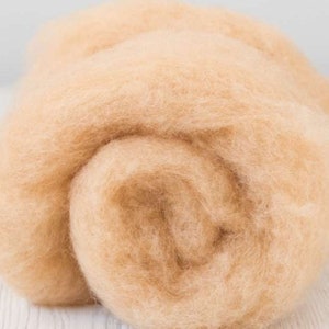 May include: A close-up of a pile of light brown wool roving. The wool is soft and fluffy, and it is perfect for felting or spinning.