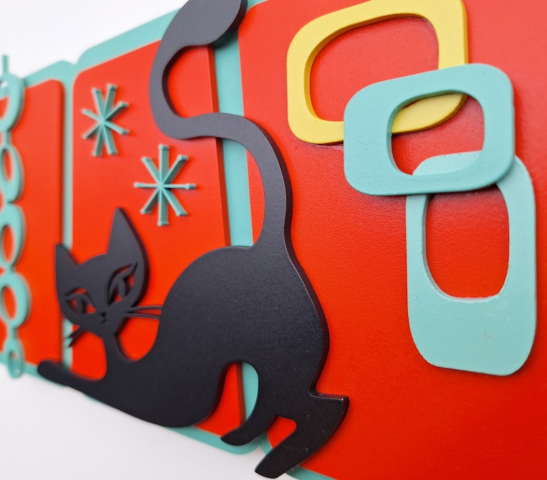 Puede incluir: Una silueta de gato negro con un fondo geom&eacute;trico de color verde azulado y rojo. El gato est&aacute; en una pose juguetona con la cola enroscada. El fondo presenta formas abstractas en verde azulado y amarillo.