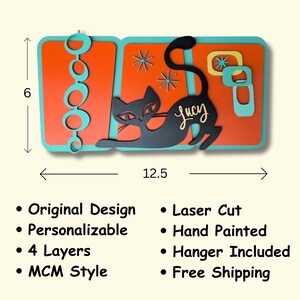Puede incluir: Una pieza de arte de pared de madera pintada a mano de varias capas que presenta una silueta de gato negro con el nombre "Lucy" en cursiva. El dise&ntilde;o es de estilo moderno de mediados de siglo con formas geom&eacute;tricas y un esquema de color turquesa y naranja. La pieza mide 31,75 cm de ancho y 15,24 cm de alto.