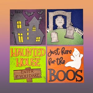 May include: Four wooden Halloween signs with different spooky themes. The first sign features a black silhouette of a haunted house with bats flying above. The second sign has a cemetery archway with a tombstone that reads "R.I.P. 1939". The third sign says "Haunted House" with a green background and an orange sign that reads "Enter if you dare". The fourth sign says "Just here for the boos" with a ghost silhouette and an orange background.