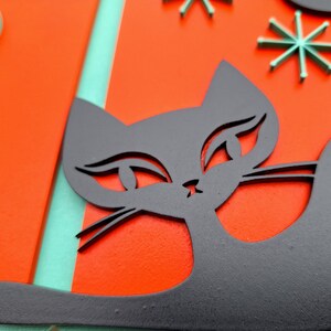 Puede incluir: Una silueta de gato negro con ojos grandes y una nariz blanca sobre un fondo rojo y turquesa. El gato mira hacia la derecha.