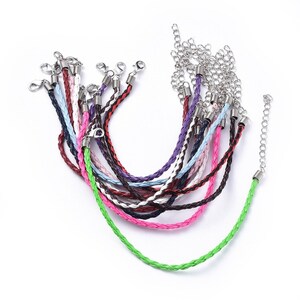 May include: A selection of braided leather necklaces in a range of colours, such as green, pink, purple, and brown. Each necklace features a silver-toned clasp and chain extender. The necklaces are shown against a white backdrop.