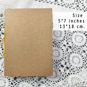 A closed kraft notebook lies on white crocheted lace with dimensions 5 by 7 inches. Use this as an Officiant Binder or a handy pocket sketchbook.