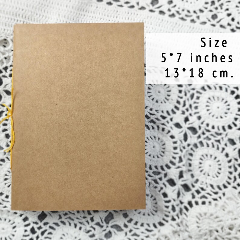 A closed kraft notebook lies on white crocheted lace with dimensions 5 by 7 inches. Use this as an Officiant Binder or a handy pocket sketchbook.