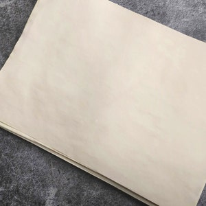 A blank sheet of coffee dyed paper with a slightly textured surface. The paper lies flat and shows the texture and pattern of aged paper.