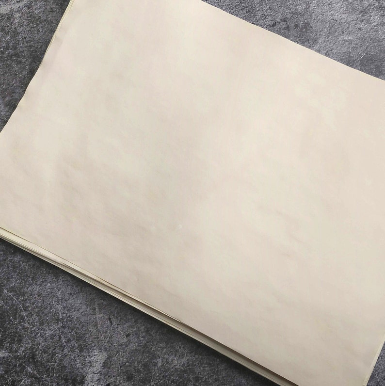 A blank sheet of coffee dyed paper with a slightly textured surface. The paper lies flat and shows the texture and pattern of aged paper.