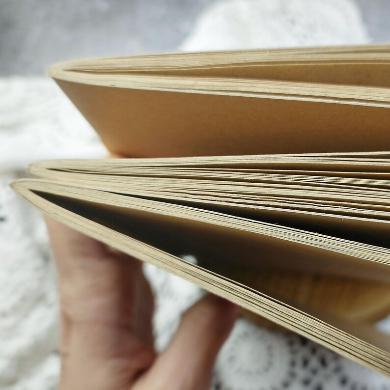 A close-up of a stack of brown paper notebooks with the pages fanned out.