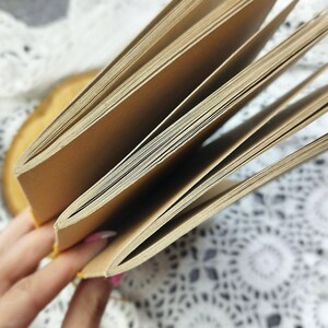 Close-up of a kraft cover notebook with open pages. The notebook is made of coffee-aged paper and has a simple design. You can order any color of paper and any color of cover.