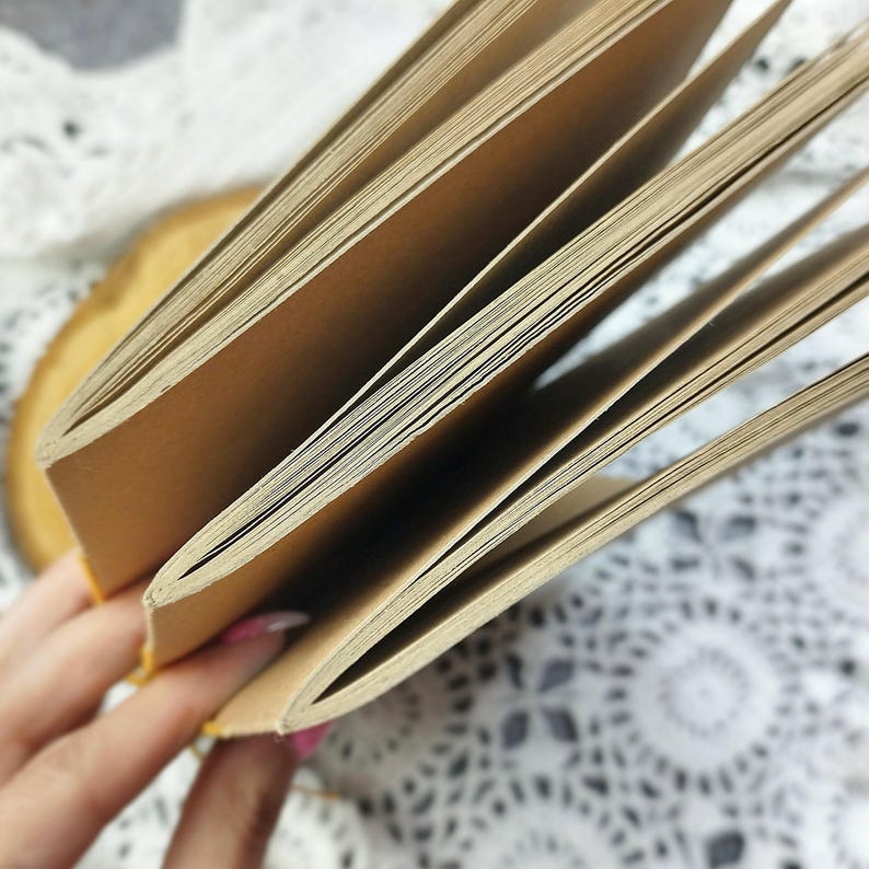 Close-up of a kraft cover notebook with open pages. The notebook is made of coffee-aged paper and has a simple design. You can order any color of paper and any color of cover.