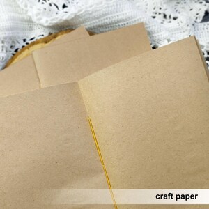 An open kraft paper notebook displays its smooth blank pages and central yellow stitching. This custom sketchbook provides a great foundation for detailed mixed media art.