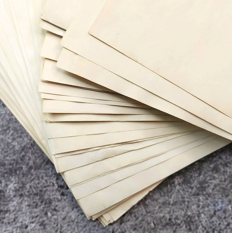 A stack of empty sheets of coffee-colored paper, arranged in a fan shape. The paper has a light texture and a cappuccino hue.