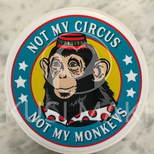 Puede incluir: Una pegatina redonda con fondo azul, amarillo y rojo. Un mono con un sombrero rojo y amarillo y una camisa de lunares rojos y blancos está en el centro de la pegatina. El texto "Not My Circus Not My Monkeys" está escrito alrededor del mono.