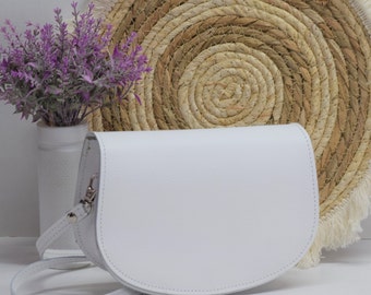 Può includere: Borsa a tracolla in pelle bianca con patta curva e chiusura argentata. La borsa ha una lunga tracolla per essere portata a spalla.