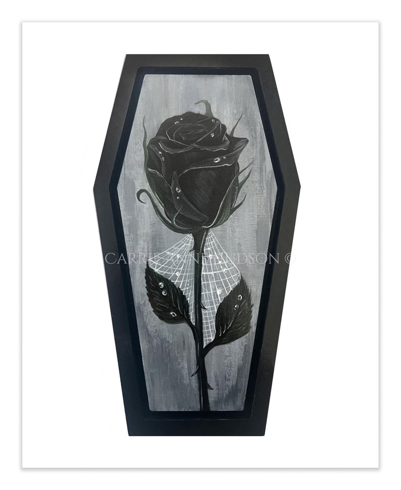 Pu&ograve; includere: Una rosa nera con gocce di rugiada sui petali e sulle foglie, incorniciata in una cornice nera a forma di bara. La rosa &egrave; circondata da una ragnatela.