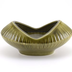 Può includere: Un vaso da fiori in ceramica verde con un design ondulato unico. Il vaso ha una forma di ciotola larga e poco profonda e una finitura liscia e lucida.